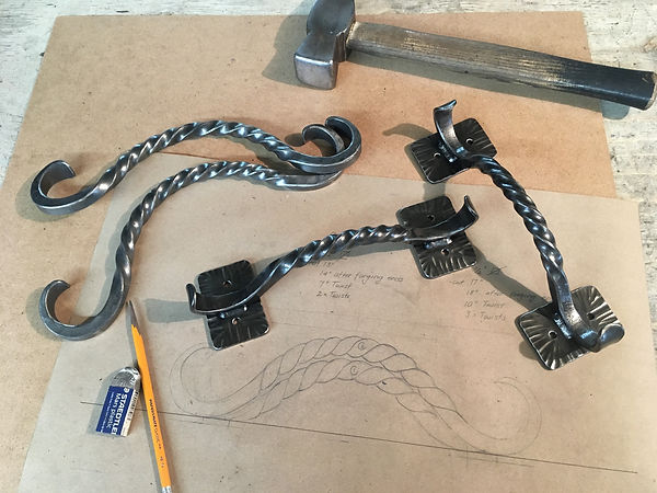 Hand-forged drawer pulls with twisted stems, laid out with the hammer and the drawing